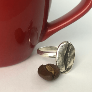 anillo de grano grande de cafe marago hecho en plata sobre una taza roja de espresso
