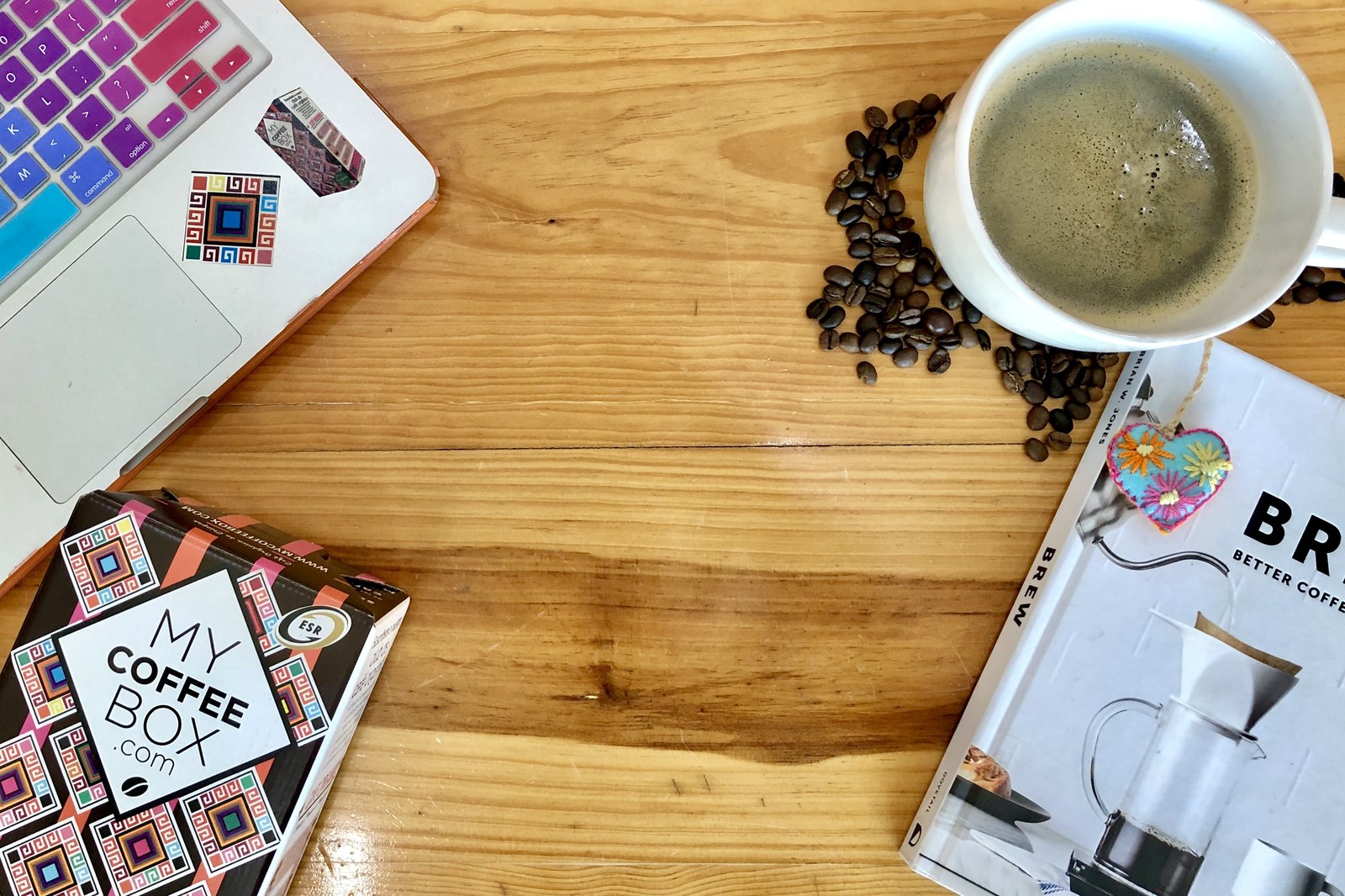 Taza de cafe negro, granos de cafe y una libreta sobre una mesa de madera clara